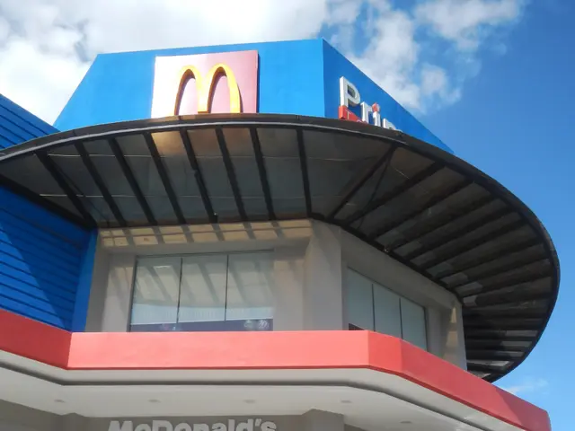The image shows a McDonald's restaurant in the middle of a parking lot, with a road in front of it....