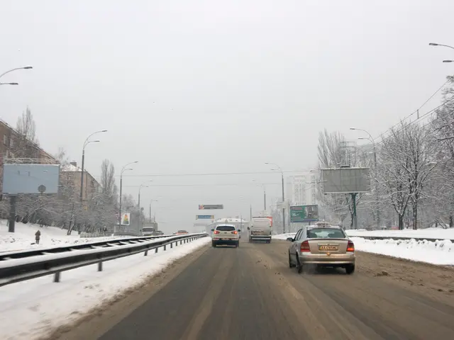 The image shows a car driving down a snowy road with snow on the ground. On either side of the...