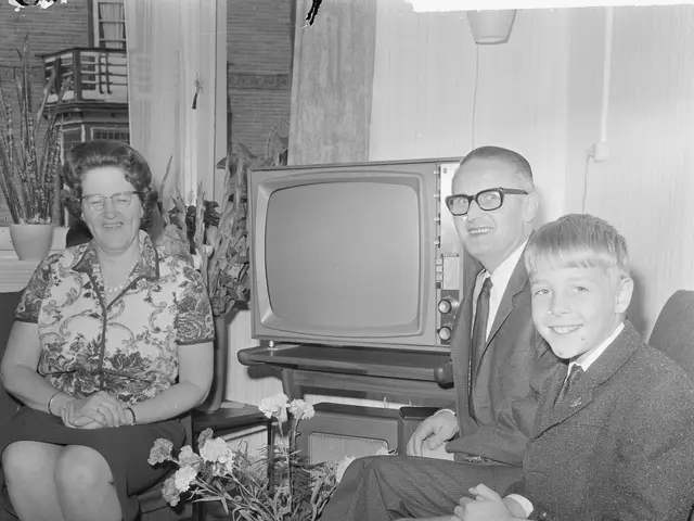 The image shows a black and white photo of a family of three - a man, woman and a boy - sitting on...