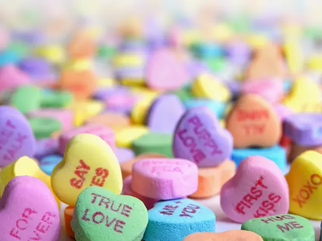 The image shows a pile of colorful conversation hearts with the words "True Love" written on them,...