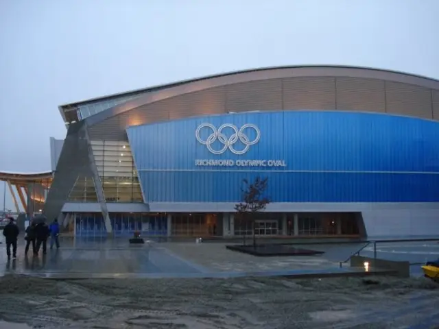 The image shows the Olympic Stadium in Sochi, Russia, with people walking on the road in front of...