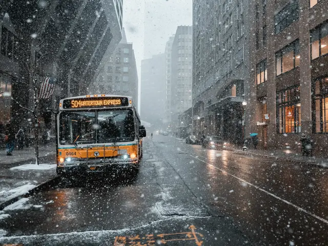 The image shows a yellow bus driving down a snowy city street, surrounded by tall buildings on...