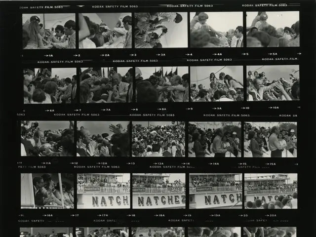 The image shows a black and white photo of a crowd of people gathered around a television screen,...