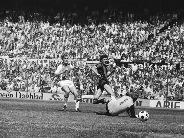 The image shows a group of men playing soccer on a field, with a crowd of spectators sitting in the...