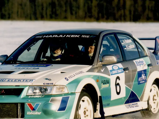 The image shows a car driving on a snowy road with two people inside wearing helmets. The car has...