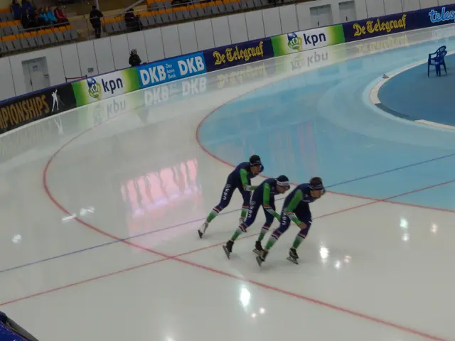 The image shows a group of three speed skaters racing down an ice rink, wearing blue and green...