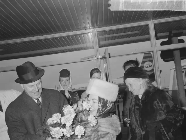 The image shows a black and white photo of a man and woman standing next to each other at an...