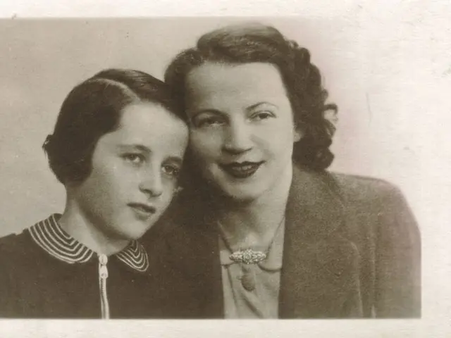 The image shows an old black and white photo of two women, one of whom is a mother and the other is...
