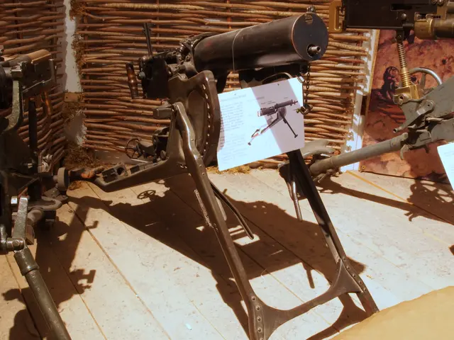 The image shows a machine gun on display in a museum, with a wooden floor beneath it and a wall in...