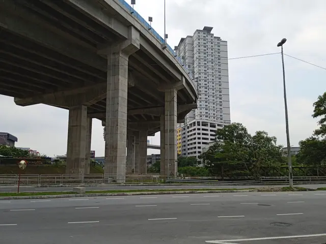 The image shows a highway with a bridge over it, a tall building in the background, street poles,...