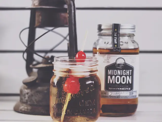 The image shows two mason jars filled with a drink sitting on top of a table next to a lantern. The...