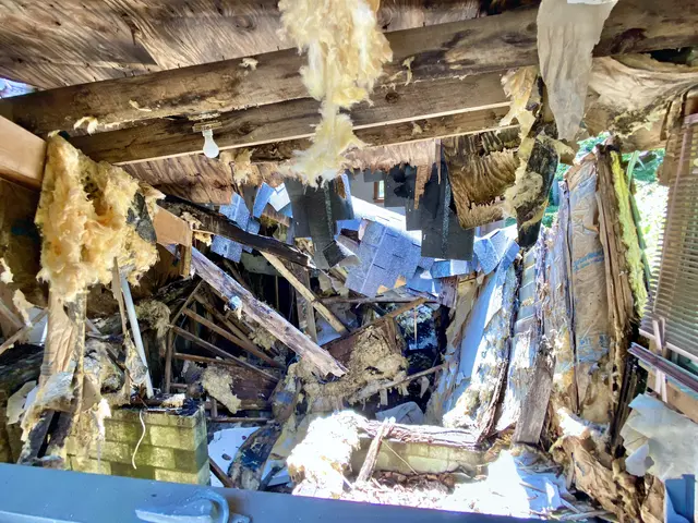 The image shows a room with a lot of debris on the floor, including wooden sticks, sheets, and...