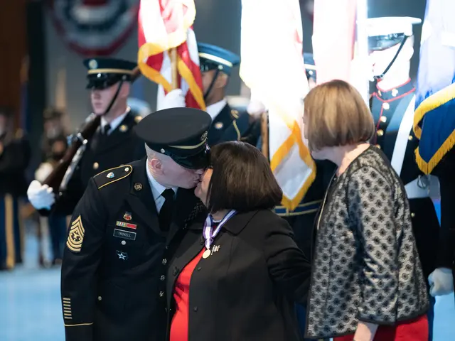 The image shows a man and woman embracing and kissing in front of a group of people wearing...