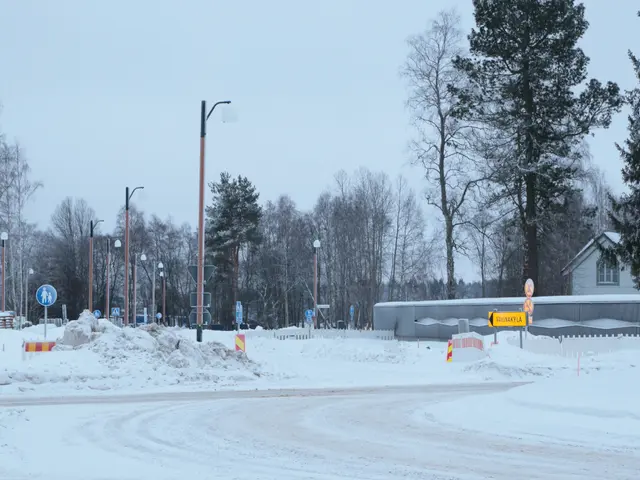 The image shows a snowy road with a lot of snow on the ground, street lights, sign boards, poles,...