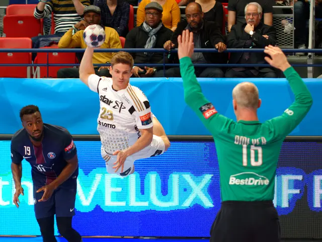 The image shows a group of men playing a game of handball on a court. In the center of the image, a...