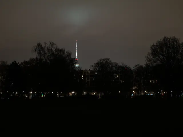 The image shows a city skyline at night with a TV tower in the background, illuminated by the...