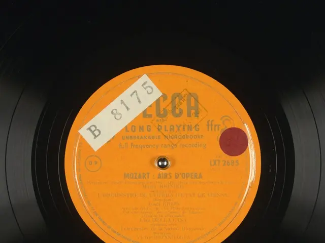 The image shows a black vinyl record with an orange label on it. The label reads "Mozart - Long...