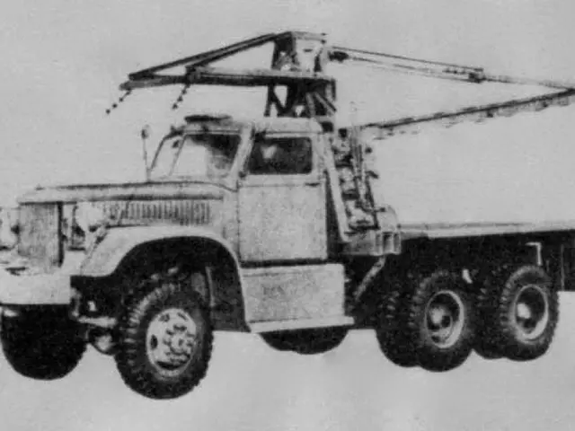 The image shows a black and white photo of a truck with a crane on the back, which is believed to...