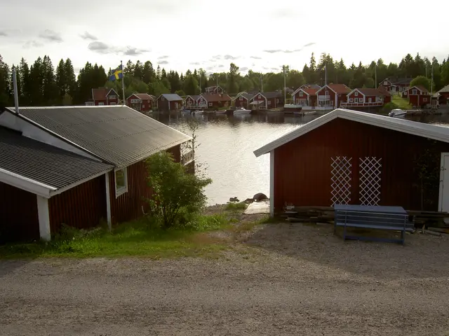 The image shows a picturesque scene of a small town with a lake in the foreground, surrounded by...