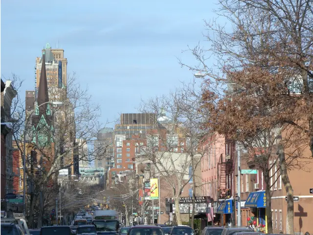 The image shows a city street filled with lots of cars driving down it, covered in snow. There are...