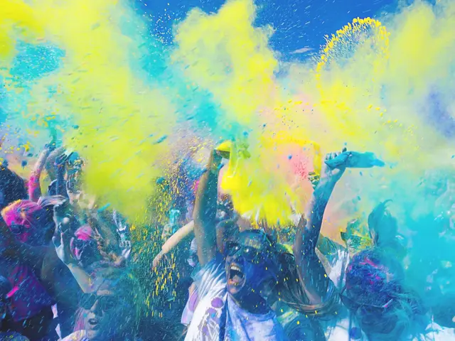 The image shows a group of people celebrating the Holi festival of colors, with colorful powder in...