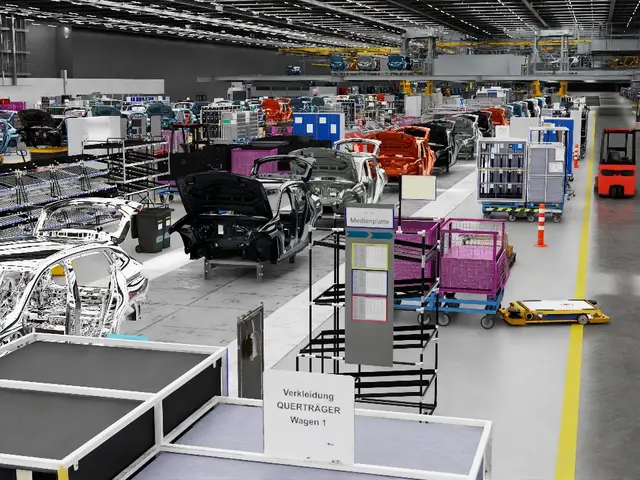 The image shows a large factory filled with lots of cars on the assembly line. There are metal...