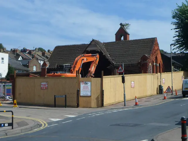 The image shows a road with a few vehicles driving on it, traffic cones, poles, boards, and a...