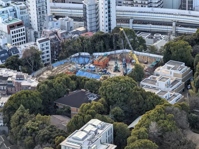 The image shows an aerial view of a construction site in the middle of a city, with buildings,...