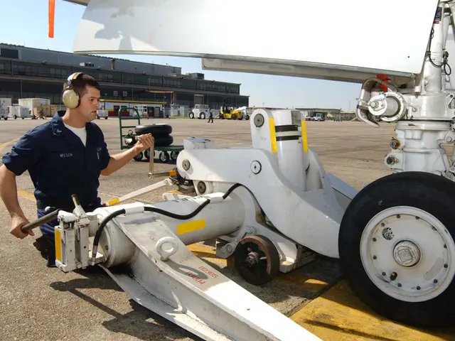 The image shows a man wearing headphones standing next to an airplane on a runway. In the...