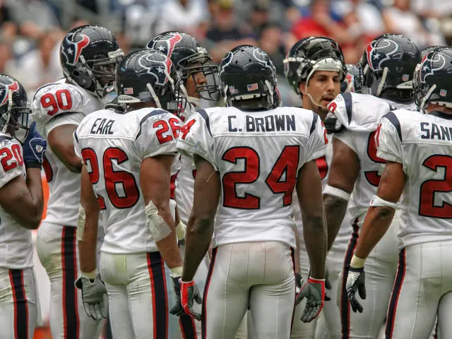 The image shows a group of Houston Texans players standing on top of a field, wearing white...