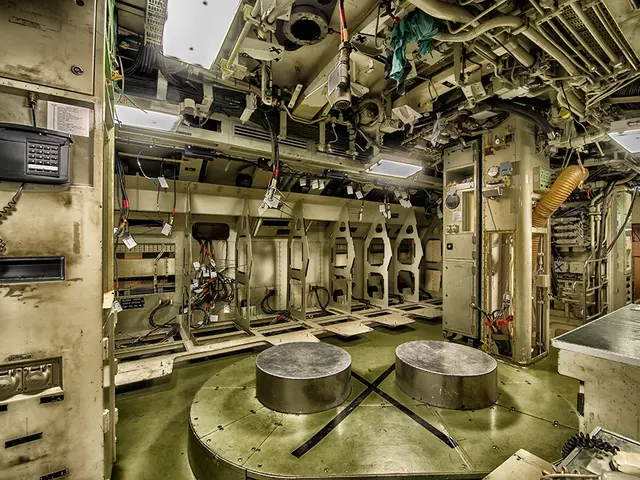 The image shows the inside of a submarine with a lot of equipment, including two round tables on...