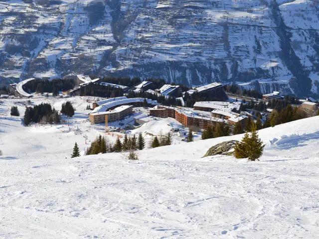 The image shows a picturesque view of a ski resort nestled in the mountains, with snow-covered...