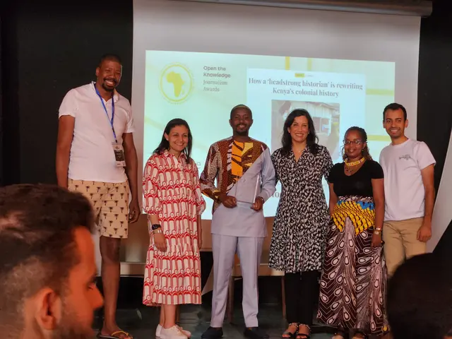 The image shows a group of people standing on top of a stage, smiling and posing for a photo. At...