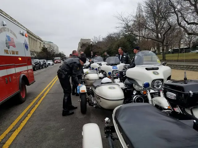 The image shows a group of police officers standing next to motorcycles on the side of a road....
