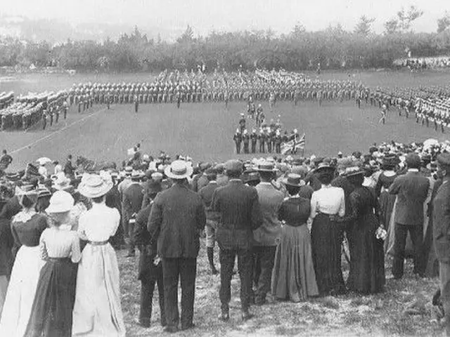 The image shows a group of people standing in front of a crowd of people, some of whom are wearing...