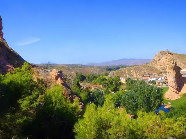 The image shows a stunning view of a small town nestled in the middle of a mountain range,...