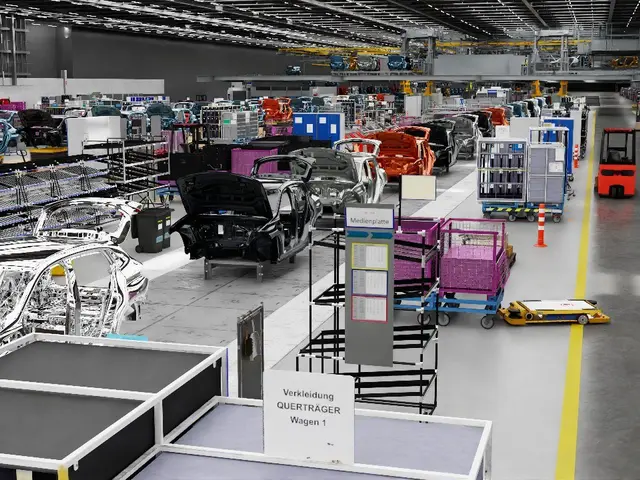 The image shows a large factory filled with lots of cars on the assembly line. There are metal...