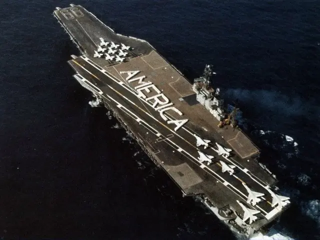 The image shows an aircraft carrier, the USS George H W Bush CVN-68, transiting the Arabian Sea. On...