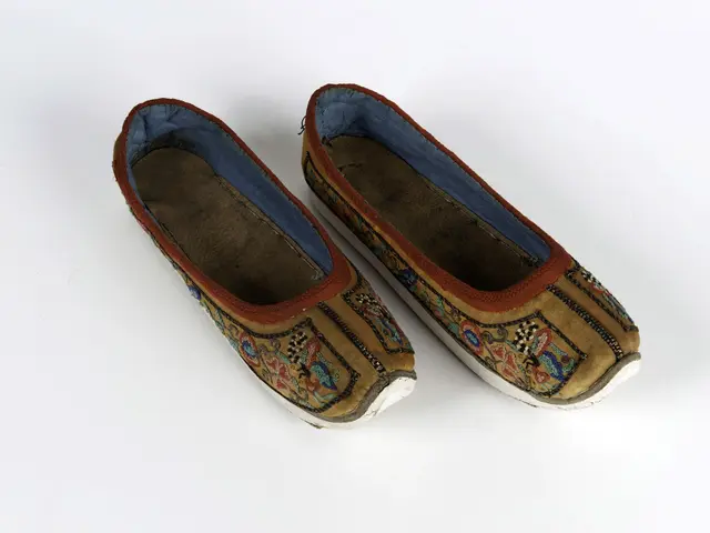 The image shows a pair of shoes with intricate embroidery on them, resting on a white surface. The...
