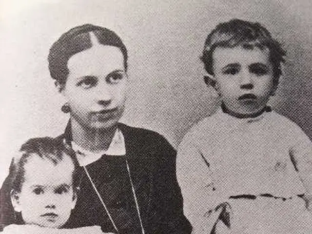 The image shows a black and white photo of a woman holding a baby in her arms, with two other...