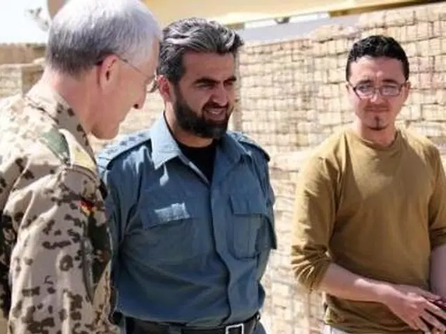 The image shows a group of men standing next to each other in front of a brick wall, with one of...