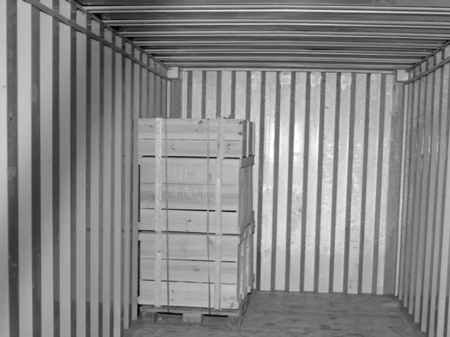 The image shows a black and white photo of a shipping container with a wooden crate inside. The...