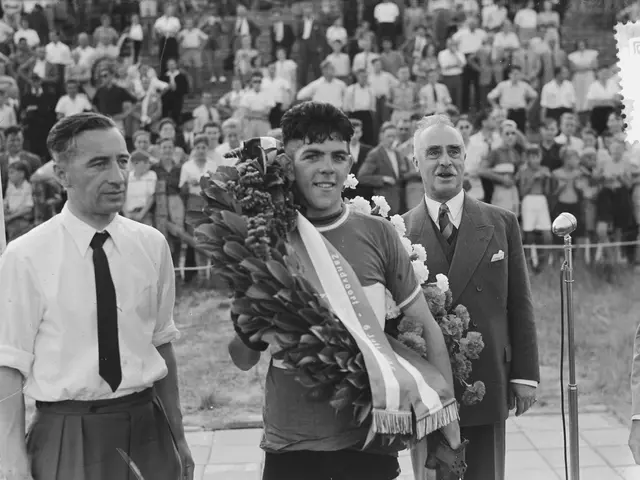 The image shows a black and white photo of a man holding a bouquet of flowers in front of a crowd....