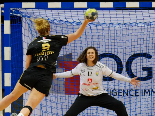 The image shows two women playing handball in front of a goal, with one of them holding a ball in...