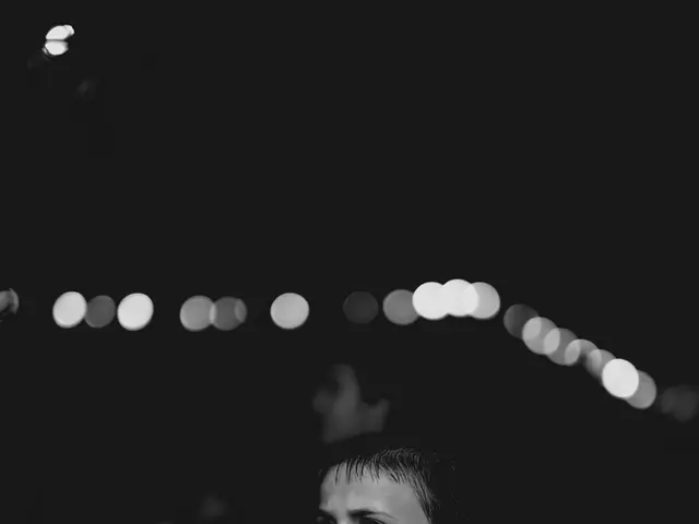 The image shows a young boy in a white shirt dancing on a dance floor surrounded by people and...