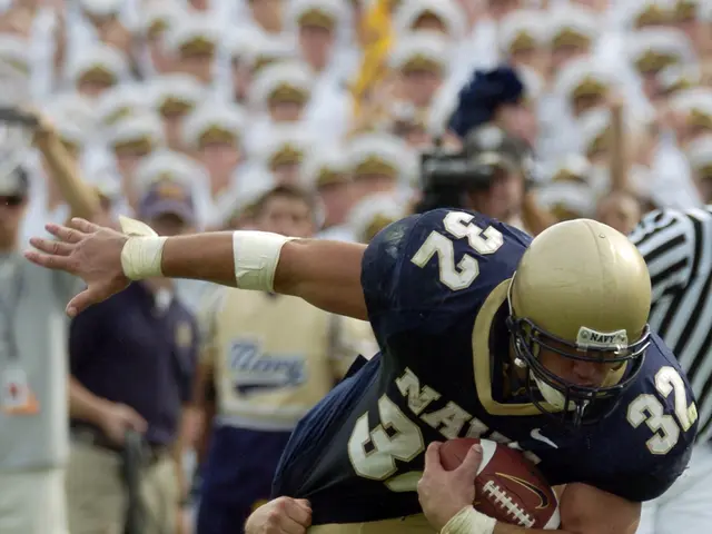 The image shows a football player being tackled by another player on the field. The player with the...