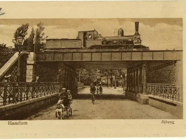 The image shows an old black and white photo of a train crossing a bridge, with a few people riding...