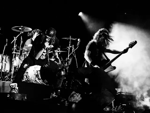 The image shows a group of people on stage playing guitars and drums, illuminated by lights and...