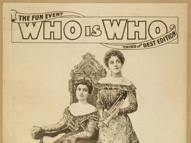 The image shows two women, one sitting on a chair and the other standing, both wearing dresses. At...