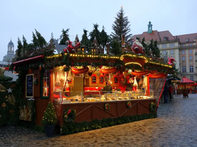 The image shows a festive Christmas market stall in the middle of a cobblestone street, surrounded...